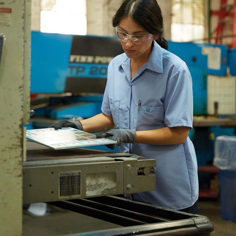 Manufacturing worker wearing a blue Dempsey Uniform womens short sleeve work shirt