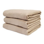 Stack of Dempsey Uniform medical linen bedspreads in beige color